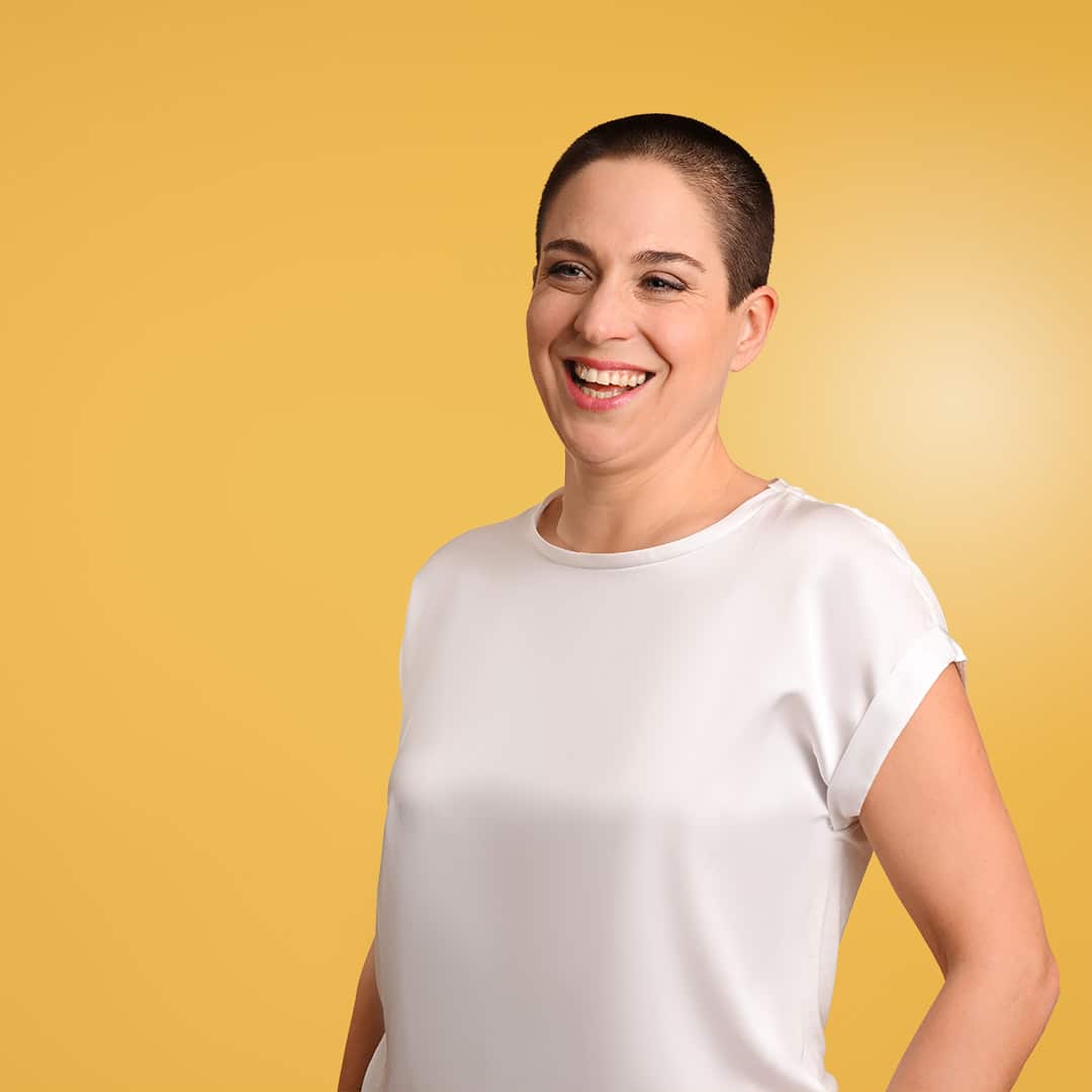 Rebekka Thommen lächelnd vor einem gelben Hintergrund – Coaching und Stressmanagement auf der Über mich Seite