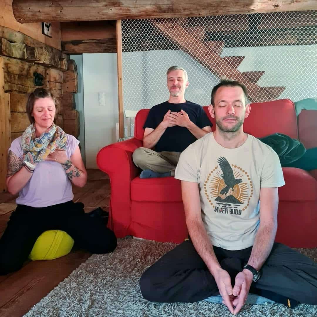 Teilnehmer beim Meditieren in einer entspannten und gemütlichen Atmosphäre, Fokus auf innerer Klarheit und Heilung.